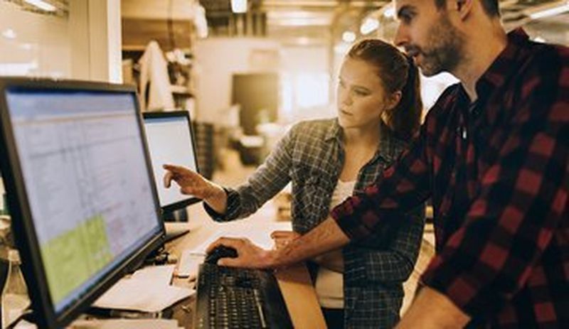 Man and woman working on large screen